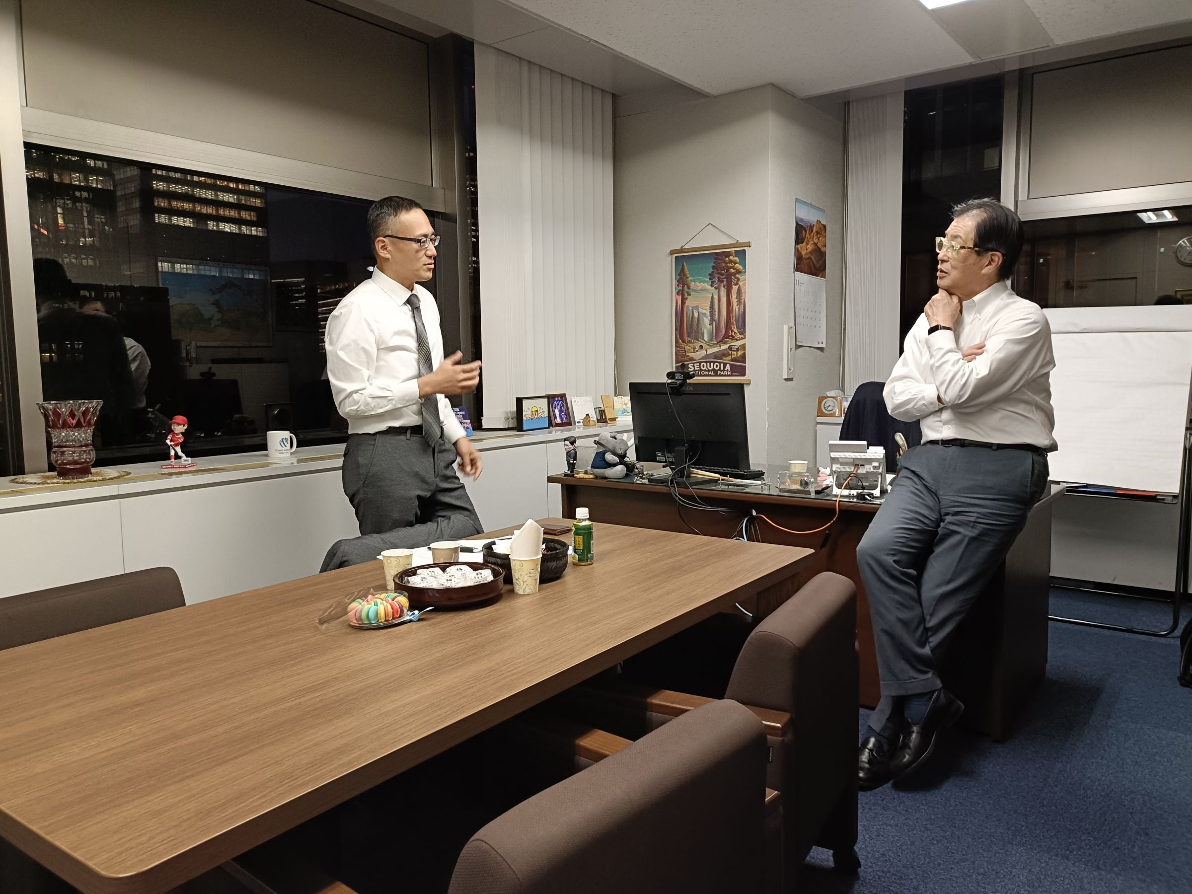 理事長室では、馬奈木先生と理事長綿引が歓談。